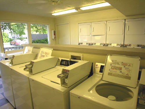 Pier Landing Apartments interior of laundry facility with washers and dryers, pay with quarters to use